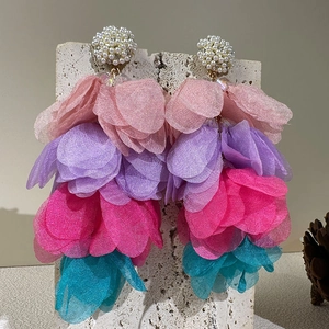 Détail de boucles d'oreilles pétales en organza et perle sur pierre de travertin