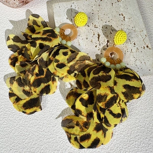 Detail of leopard print fabric flower earrings with amber resin ring and yellow beads