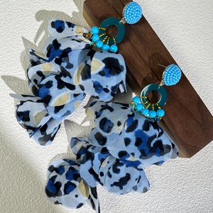 Detailed close-up of blue leopard print fabric petals and beaded bohemian earrings