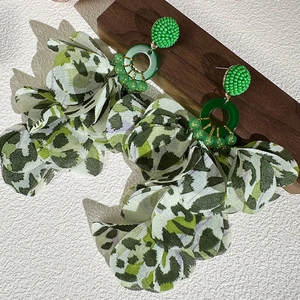 Detail of green chiffon leopard petal earrings with resin ring in bohemian style