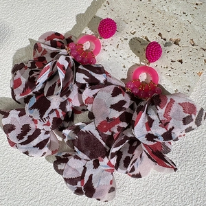 Macro shot of tiered leopard print fabric earrings with beads on textured stone