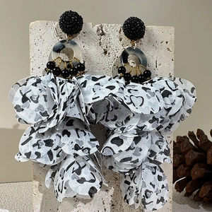 Detail of handmade leopard print fabric flower earrings with black beads on a stone stand
