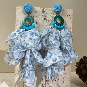 Detail of bohemian handmade floral earrings with blue fabric petals on stone