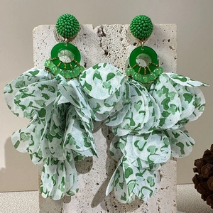 Detail of green floral fabric leaf tassels and beaded accents on long drop earrings
