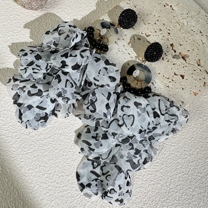 Close-up of handmade fabric floral earrings with leopard print petals and marble ring