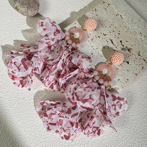 Detail of pink fabric flower earrings with beaded studs and resin rings on stone display