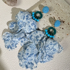 Macro detail of Bohemian floral earrings with blue chiffon tassels and beaded resin rings