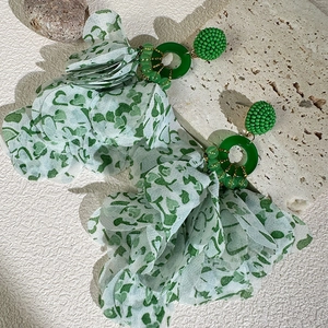 Macro shot of long fabric flower tassel earrings with green beads and white chiffon layers