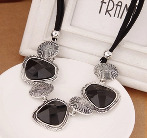 Détail du collier géométrique vintage avec pendentif en cristal noir et texture argentée