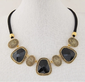 Vue détaillée de gemmes noires géométriques et pendentifs dorés à texture spirale