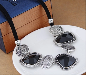 Détail du collier bohème avec de gros cristaux noirs et du métal argenté à texture spirale