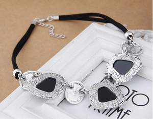 Gros plan de pendentifs bohèmes en métal avec incrustations de résine noire et texture martelée