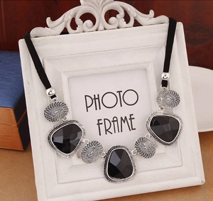 Détail de pendentifs en cristal noir avec texture en spirale argentée sur chaîne corde