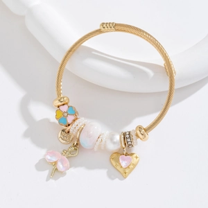 Gold braided bracelet with pearl beads and pink heart floral charms on white background