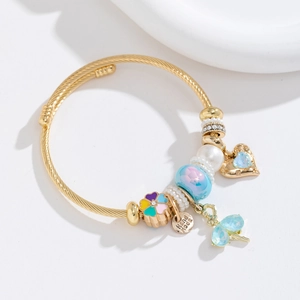 Detail of gold woven steel bracelet featuring enamel flowers, pearls and heart charms
