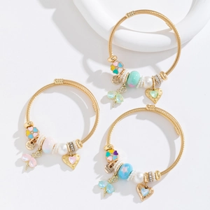 Three-piece gold beaded bracelet set with heart charms and pearls on white surface