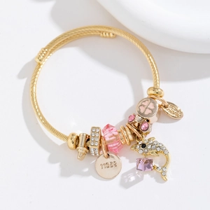Détail du bracelet doré ajustable avec des breloques dauphin en cristal et trèfle rose