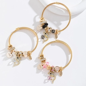 Trois bracelets en fil doré avec breloques dauphin en cristal et étiquettes