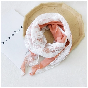 Detail of pink cotton scarf with white floral lace trim on decorative wooden tray