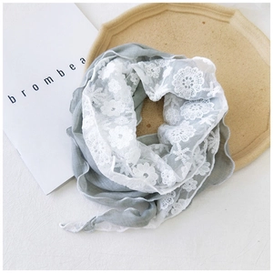 Detail of light green cotton linen scarf featuring floral lace edges and soft texture