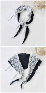 Detail of black cotton scarf with delicate white floral lace patchwork and wavy edges
