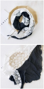 Detail of floral lace embroidery and black pleated fabric on a modern triangle scarf