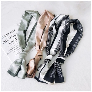 Detail view of four patterned skinny silk scarves on elegant white textured fabric