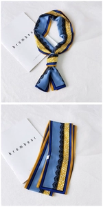 Detail of skinny silk scarf featuring blue and yellow contrast patterns on white background