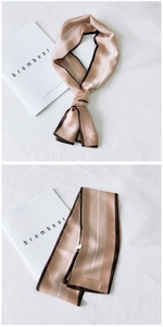 Close-up of champagne striped skinny scarf with brown edges and silky texture detail