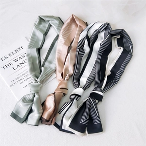 Elegant striped satin skinny scarves in diverse colors displayed on linen with a book