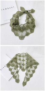 Detailed close-up of dark green floral embroidery on sheer lace triangular scarf