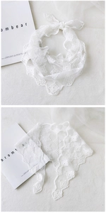 Detailed close-up of white floral embroidery and scalloped lace edges on a mesh scarf