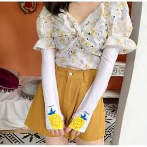 Detail of white cooling arm sleeves with pineapple print and thumb hole design