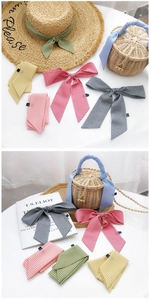 Détail de foulards en soie à carreaux colorés noués sur un chapeau de paille et panier
