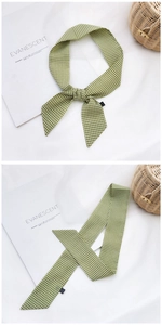 Détail d'un foulard en soie à carreaux vert et blanc noué en nœud sur fond blanc pur