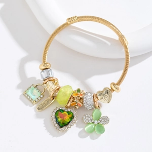 Détail du bracelet doré avec cristal de cœur vert et breloques cœur Love