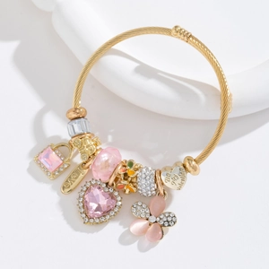 Détail du bracelet torsadé doré avec cœurs en cristal rose et breloques Love