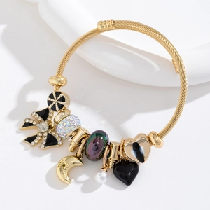 Bracelet à breloques dorées avec cristaux, cœur noir et papillon sur support blanc chic