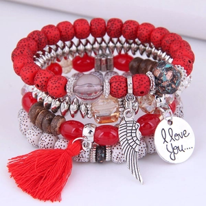 Detail of bohemian layered beaded bracelet featuring red tassels and a silver heart charm