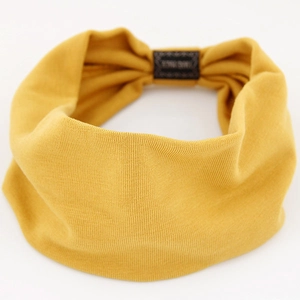 Bright yellow knitted yoga headband with elastic texture and black woven label detail