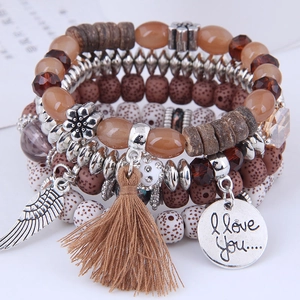 Macro view of Bohemian layered beaded bracelet with silver wing charm and tassel