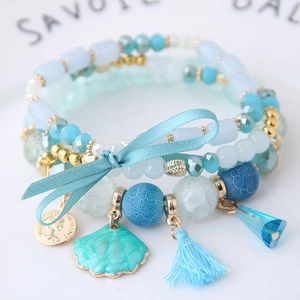 Pulsera bohemia multicapa con lazo azul, colgante de concha y detalles de borla