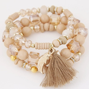 Multilayer beaded bracelet with wing charm and tassel in champagne tones