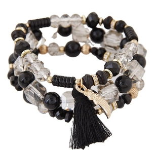 Bohemian multi-layer beaded bracelet with black tassel and golden feather charm on white background