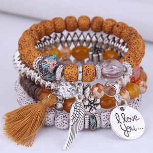 Detail of bohemian layered bracelet with silver heart charm and yellow tassel fringe
