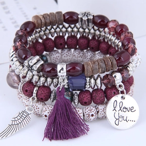 Detail of bohemian multilayer beaded bracelet with purple tassel and heart wing charms