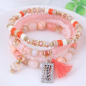 Bracelet multi-rangs bohème avec perles roses, pompons et pendentif Happy doré
