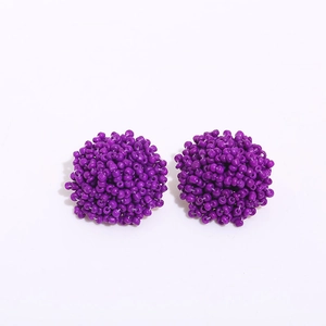 Close-up of handmade bohemian purple seed bead spherical stud earrings on white