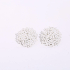 Detail of white handmade beaded ball stud earrings with intricate woven seed bead texture