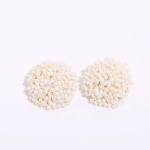 Detailed view of handmade bohemian white seed bead stud earrings in a hemispherical shape